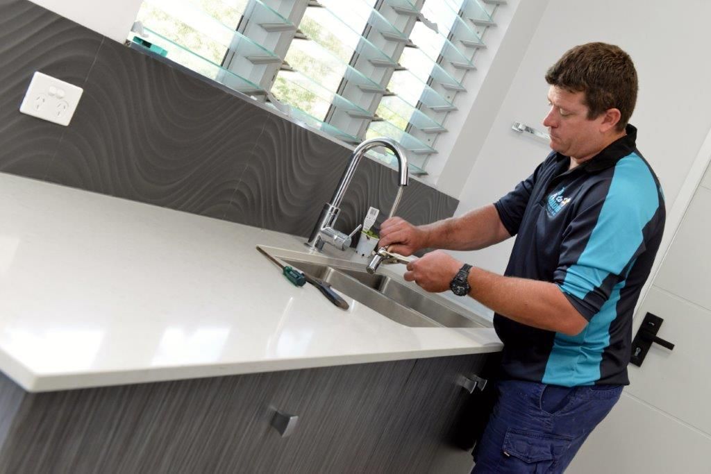 Plumber Fixing a Faucet in a Modern Bathroom — Top To Bottom Plumbing in Garbutt, QLD