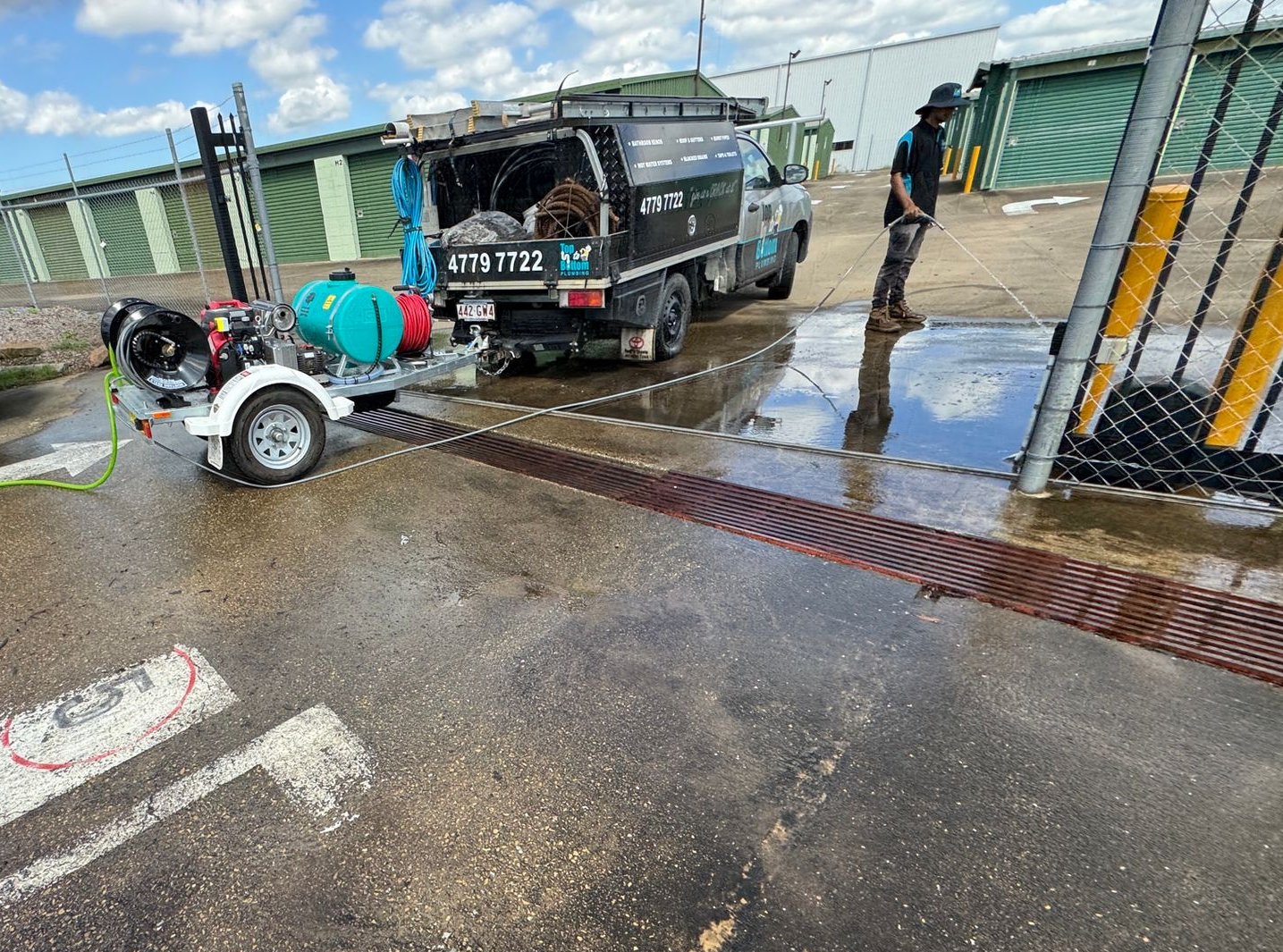 A Man Is Working on A Heating System While Holding a Clipboard — Top To Bottom Plumbing in Garbutt, QLD