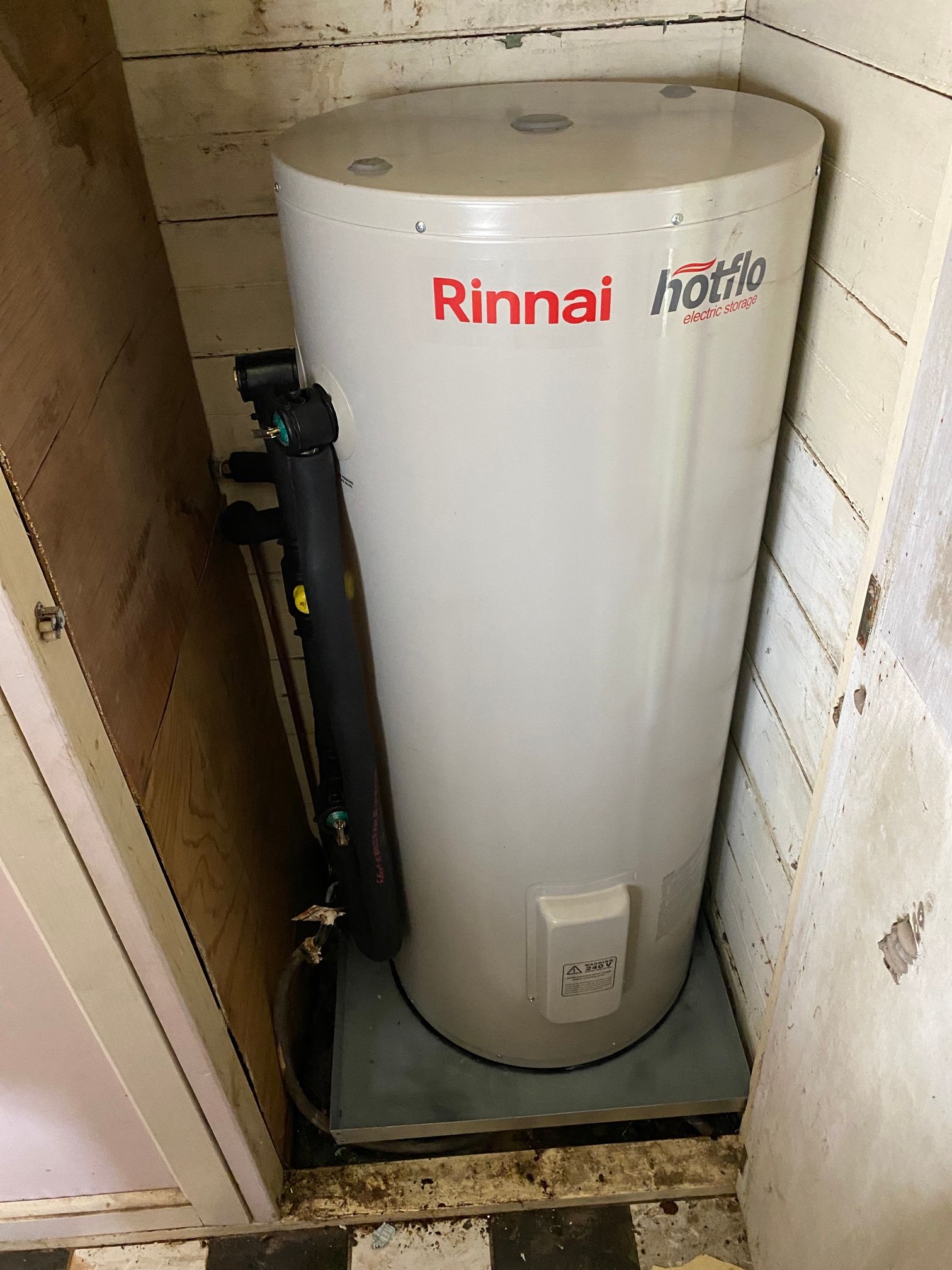 A Man Is Working on A Water Heater in A Room — Top To Bottom Plumbing in Garbutt, QLD