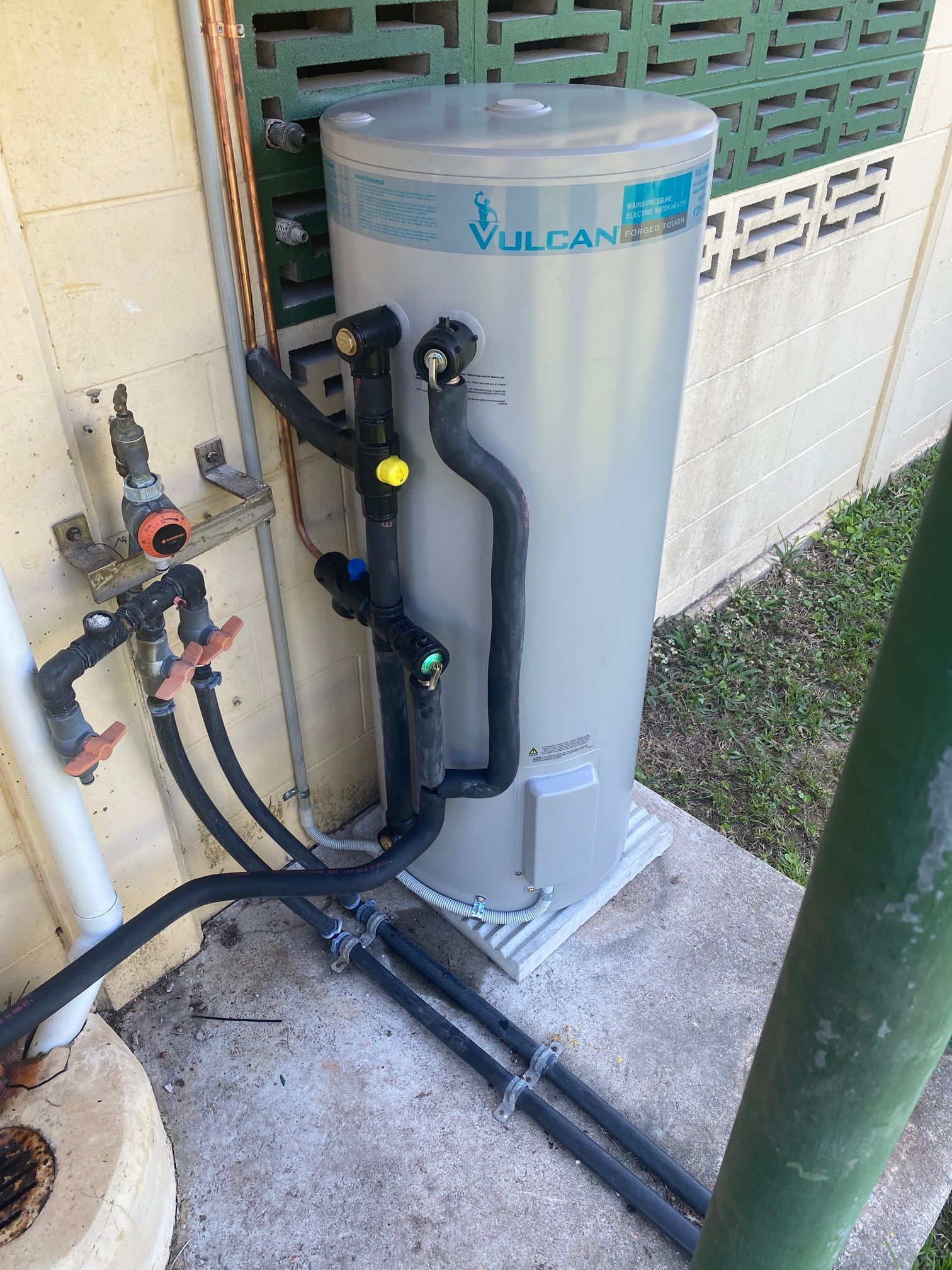 A Large White Water Heater Is Sitting Outside of A House — Top To Bottom Plumbing in Garbutt, QLD