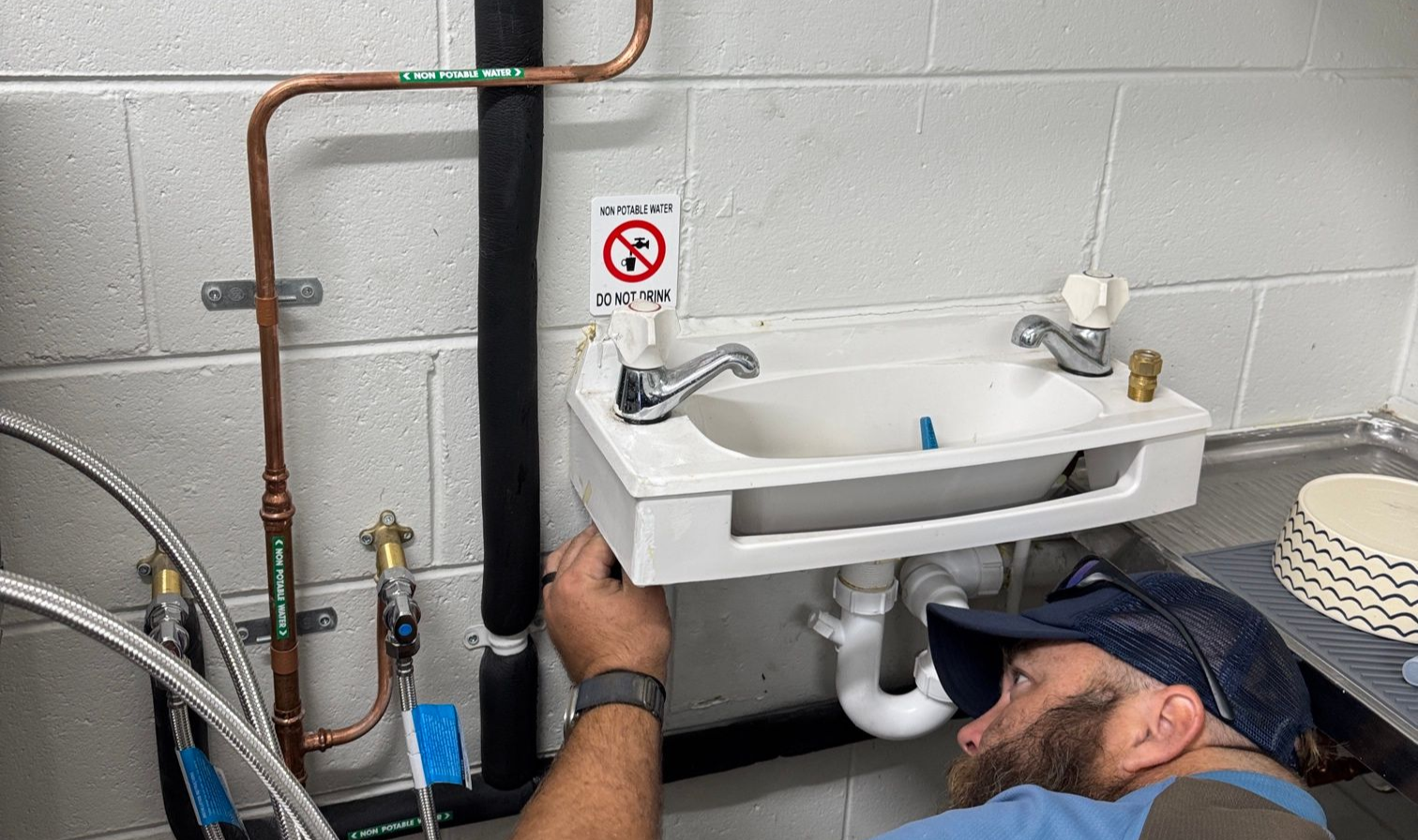 Person Wearing Gloves Adjusting Blue Pvc Pipes in A Trench Filled with Soil — Top To Bottom Plumbing in Garbutt, QLD