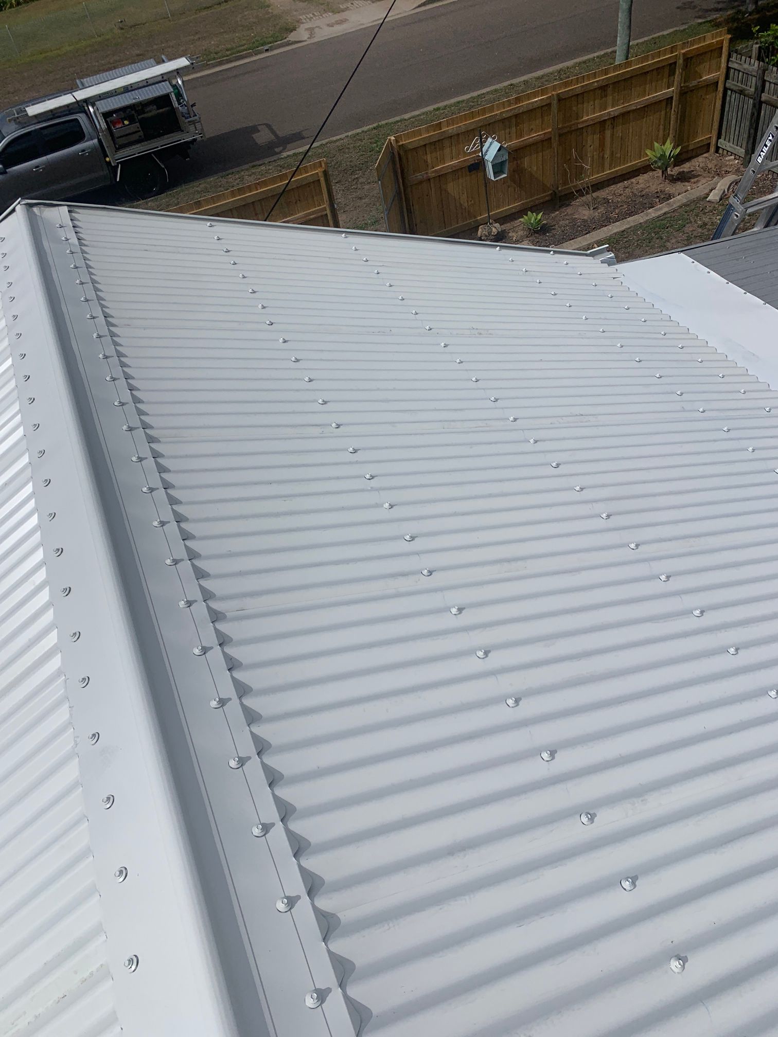 A Man Is Using a Drill to Fix a Roof — Top To Bottom Plumbing in Garbutt, QLD
