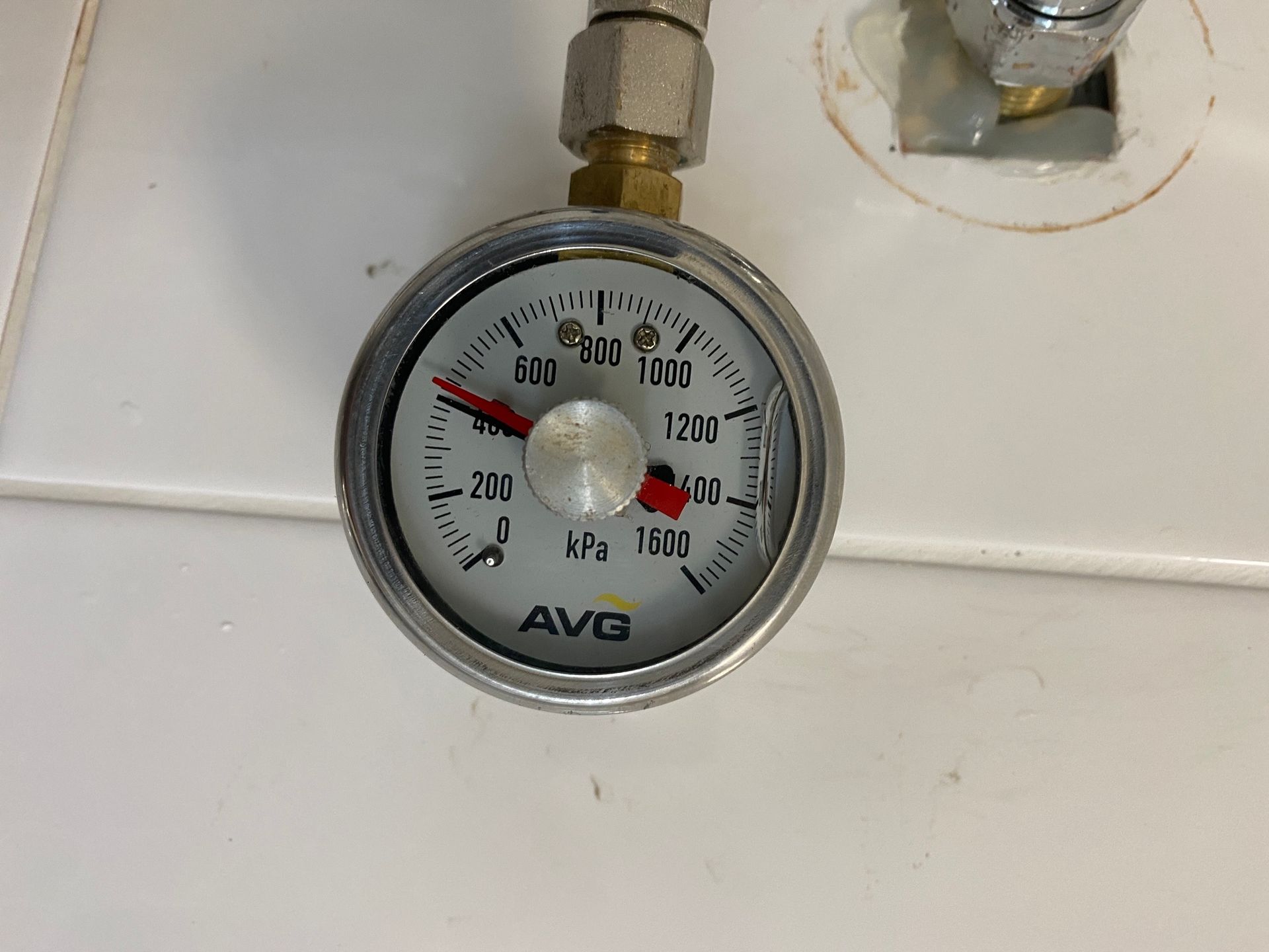 A Person Is Holding a Pressure Gauge Next to A Shower Head — Top To Bottom Plumbing in Garbutt, QLD