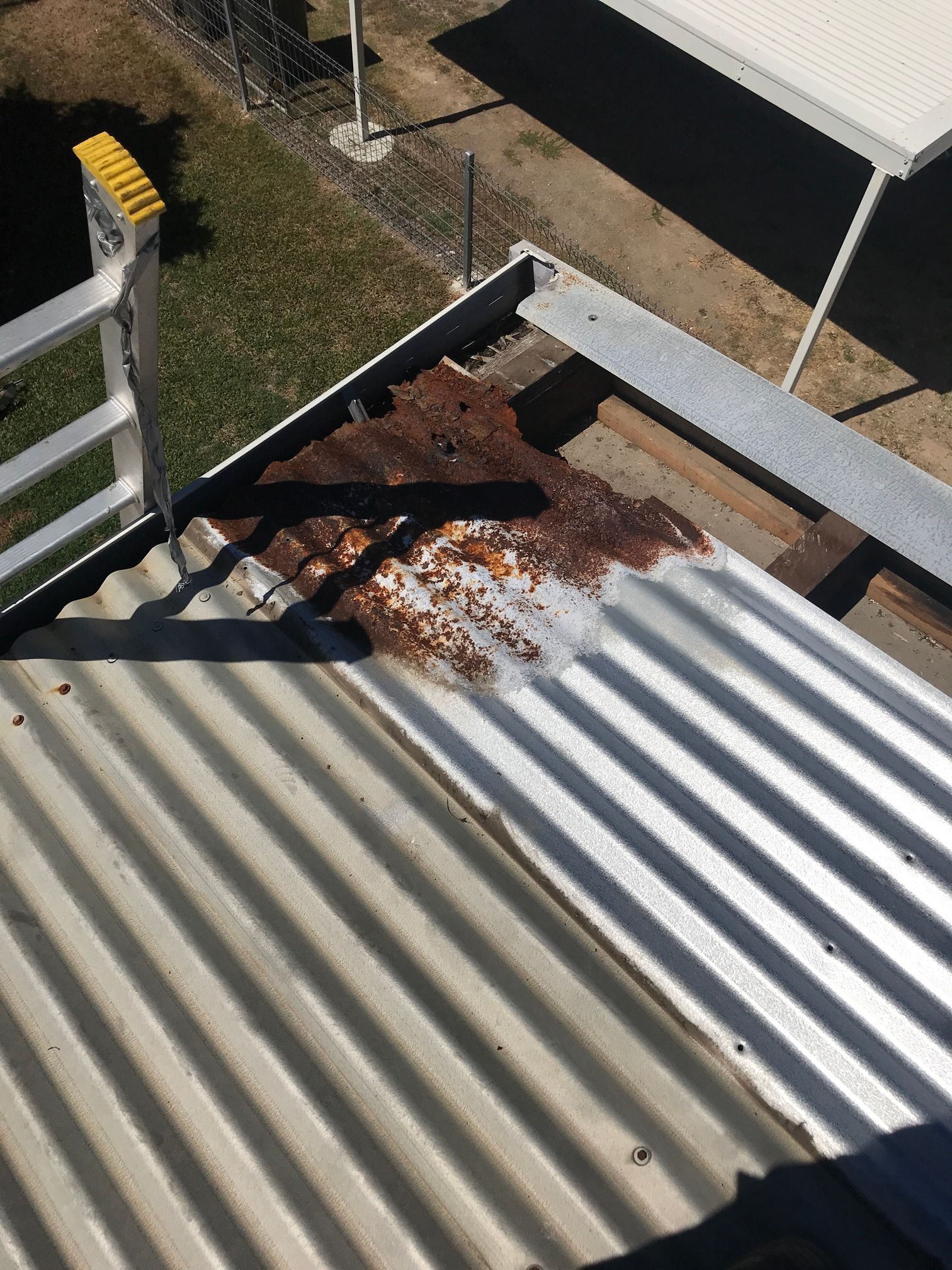 A Man Wearing a Hard Hat and Safety Vest Is Working on A Roof — Top To Bottom Plumbing in Garbutt, QLD