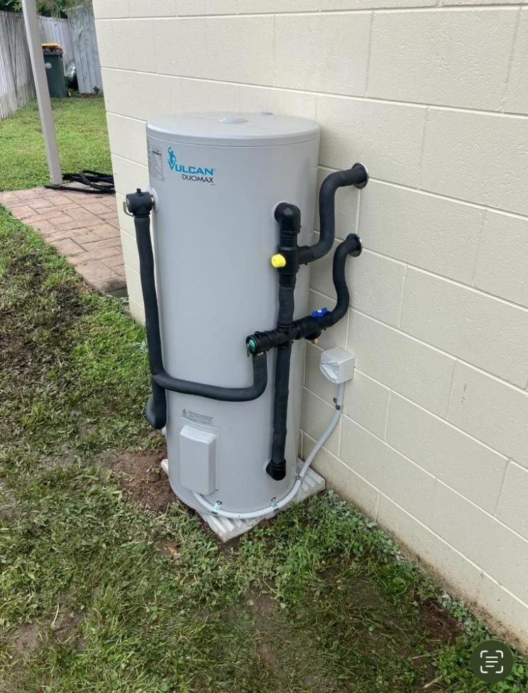 A White Water Heater Is Sitting on The Side of A Brick Building — Top To Bottom Plumbing in Garbutt, QLD