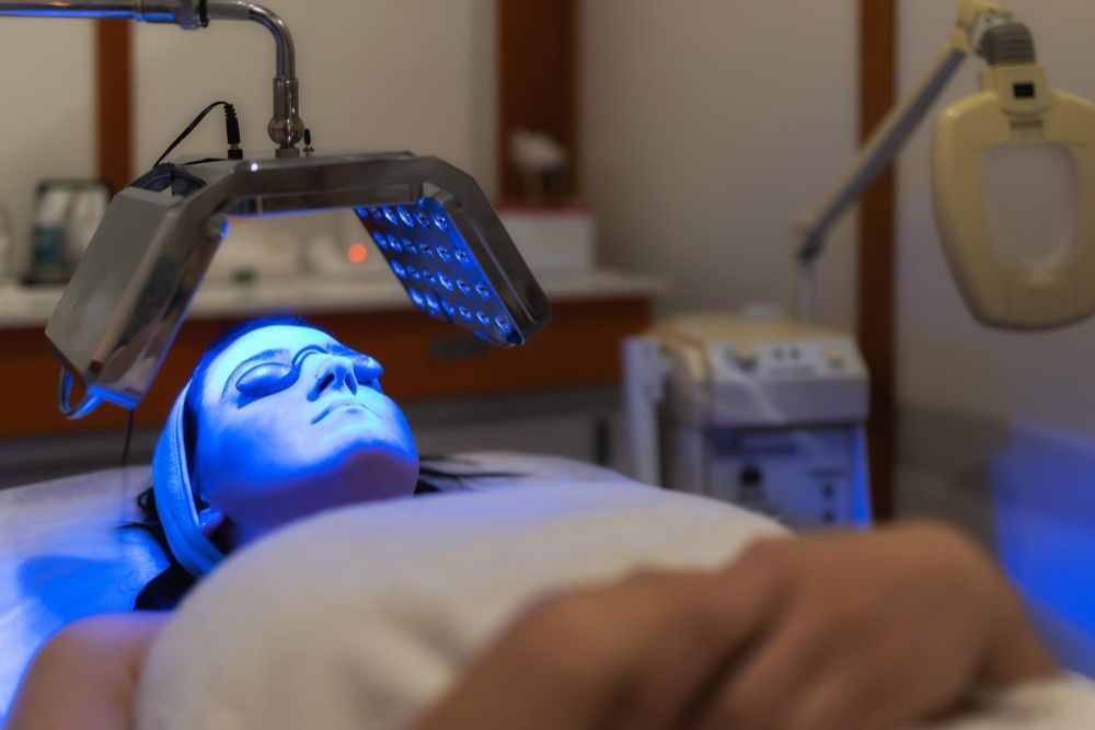 Blue facial LED mask treatment in a spa, with a person lying under the light