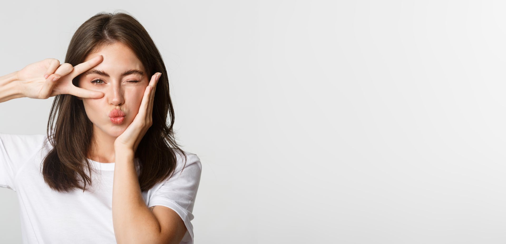 Woman touching her face with fingers, looking tired or in discomfort against a light background