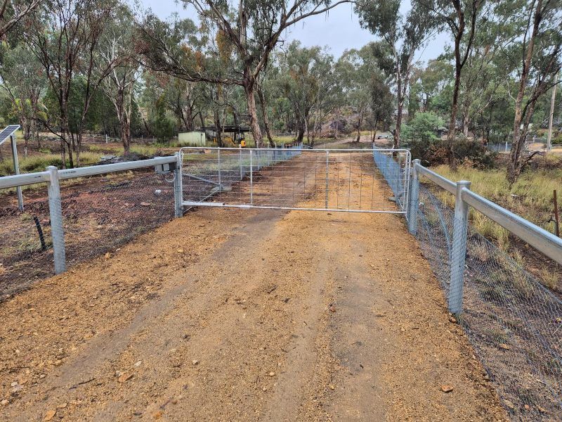 A Dirt Road with A Metal Gate and Fence — Barry Brown Rural Contracting Service in Tinonee, NSW