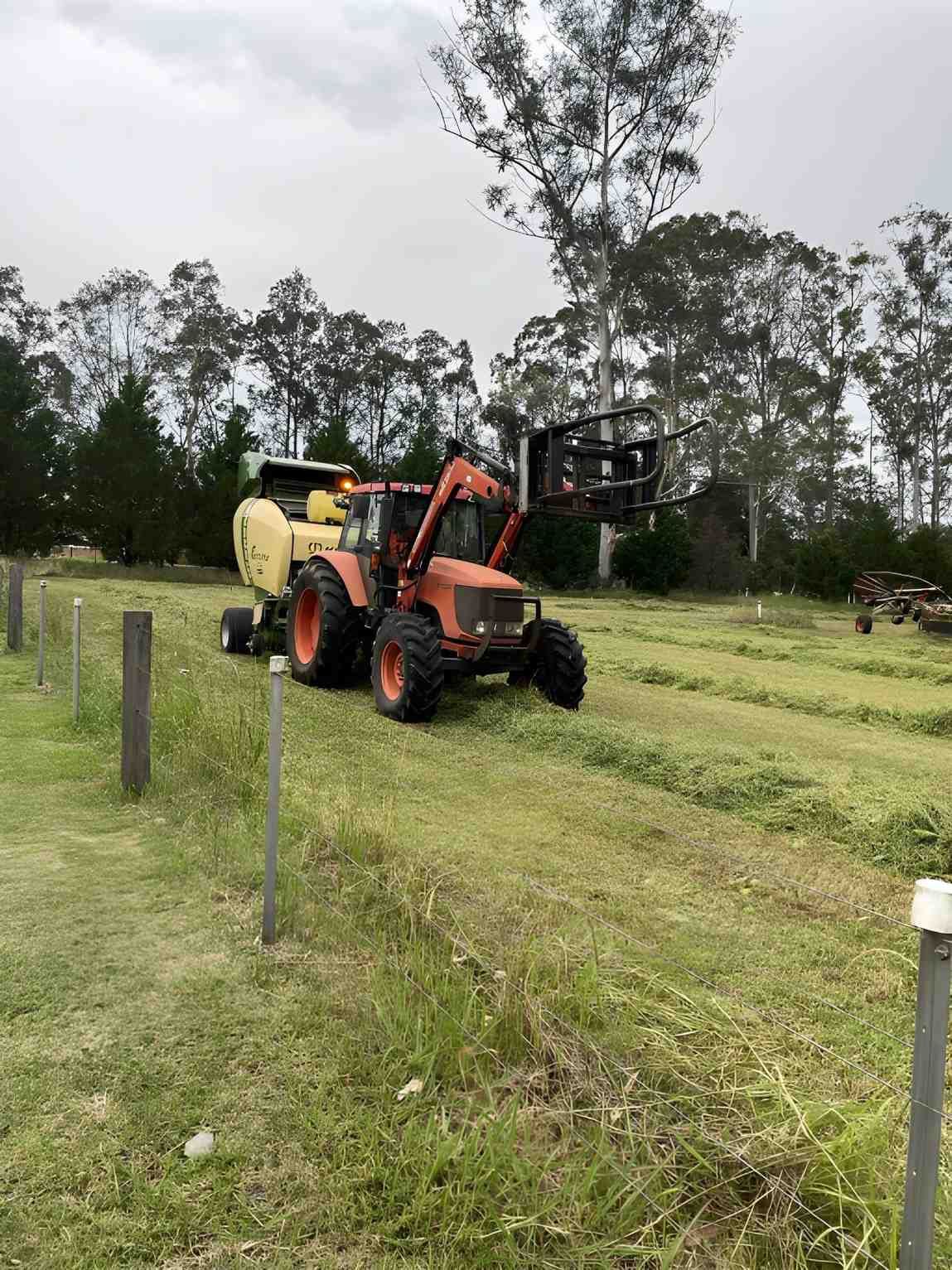 A Tractor with Hay Baler on A Grassy Field — Barry Brown Rural Contracting Service in Tinonee, NSW