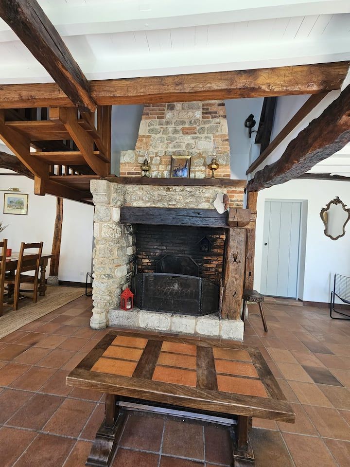 Salon rustique avec cheminée en pierre, poutres en bois et table basse carrelée au premier plan