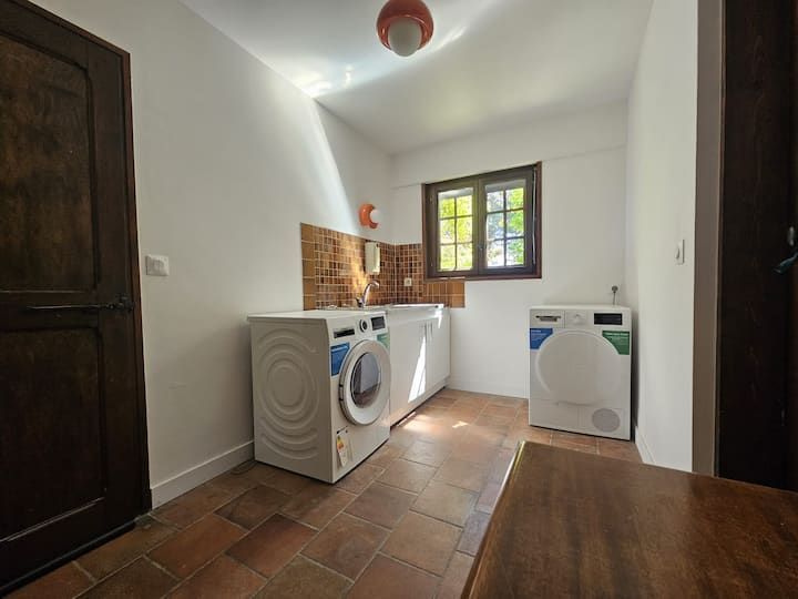 Buanderie avec lave-linge et sèche-linge, sol en carrelage de terre cuite et petite fenêtre.