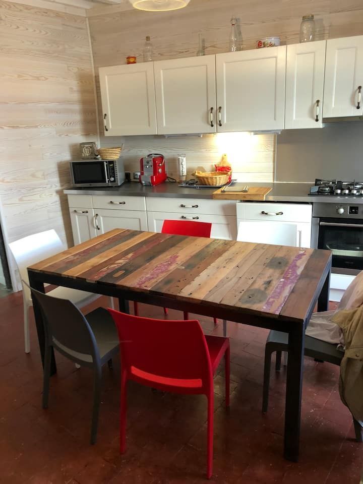 Cuisine moderne avec placards blancs, table en bois et chaises noires, rouges et grises