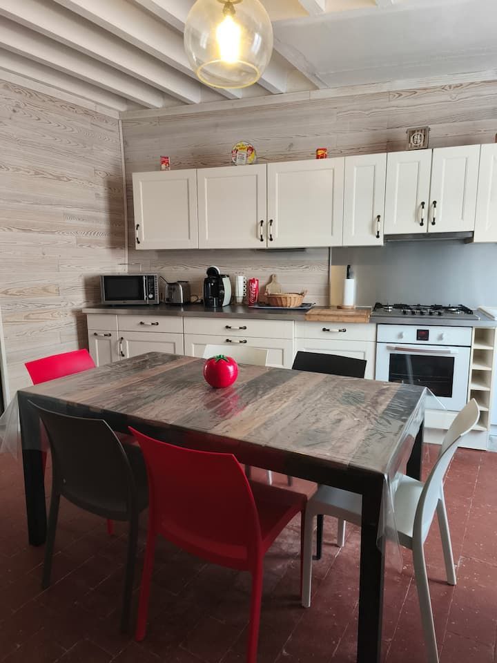 Petite cuisine avec placards blancs, table à manger foncée, chaises rouges et micro-ondes sur le plan de travail