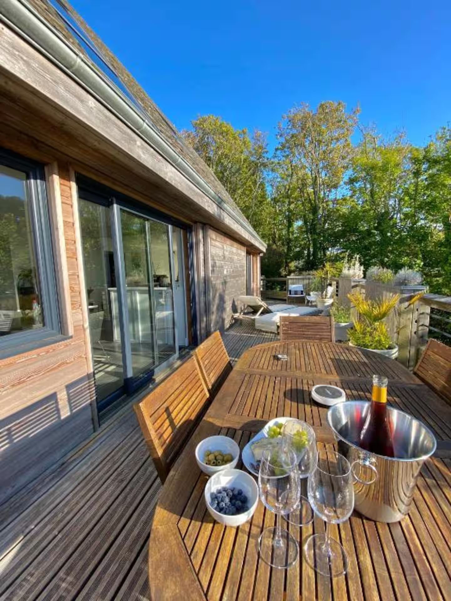 Une table en bois avec une bouteille de vin et des verres dessus.