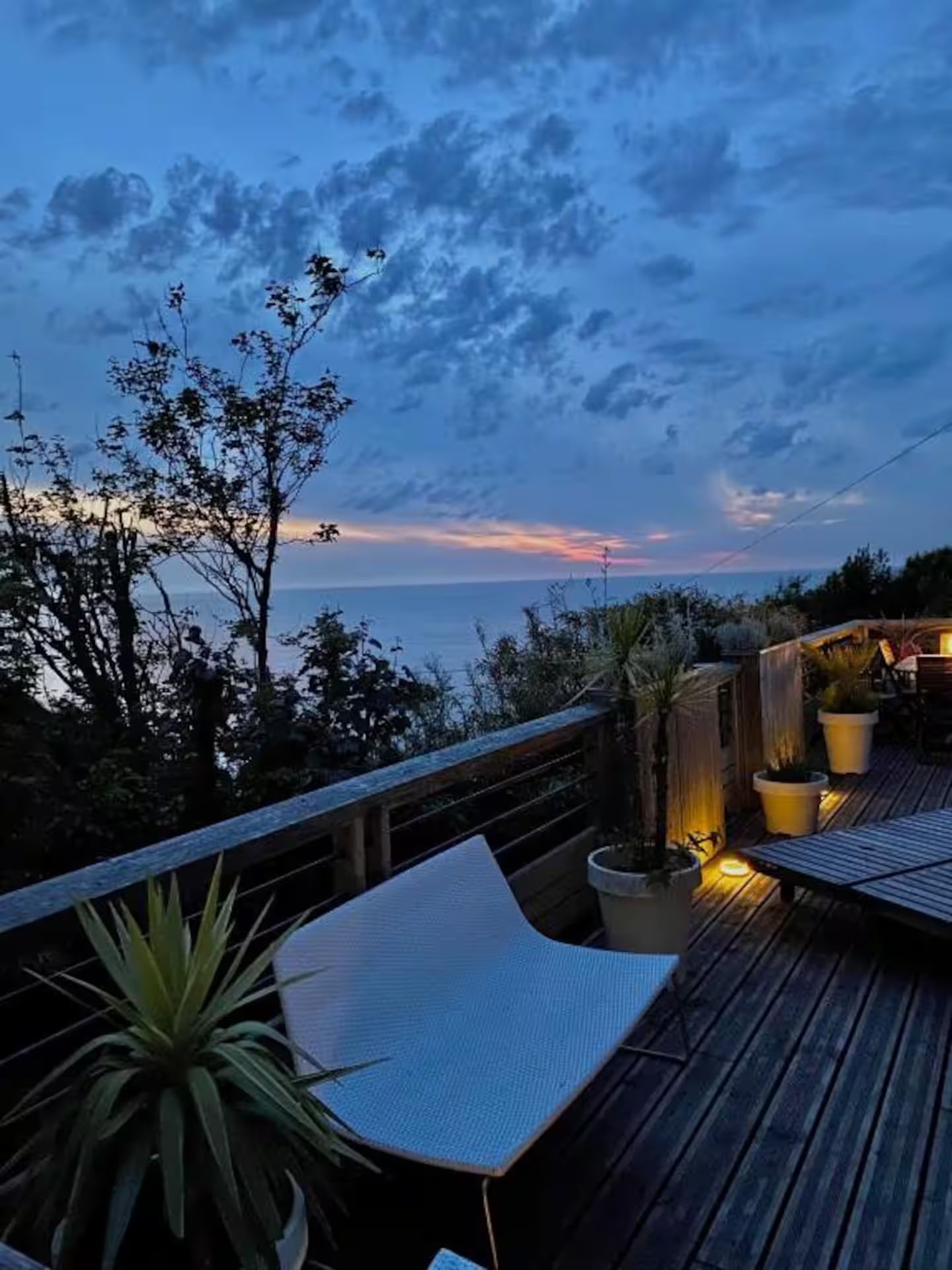 Une terrasse en bois avec vue sur l'océan la nuit.