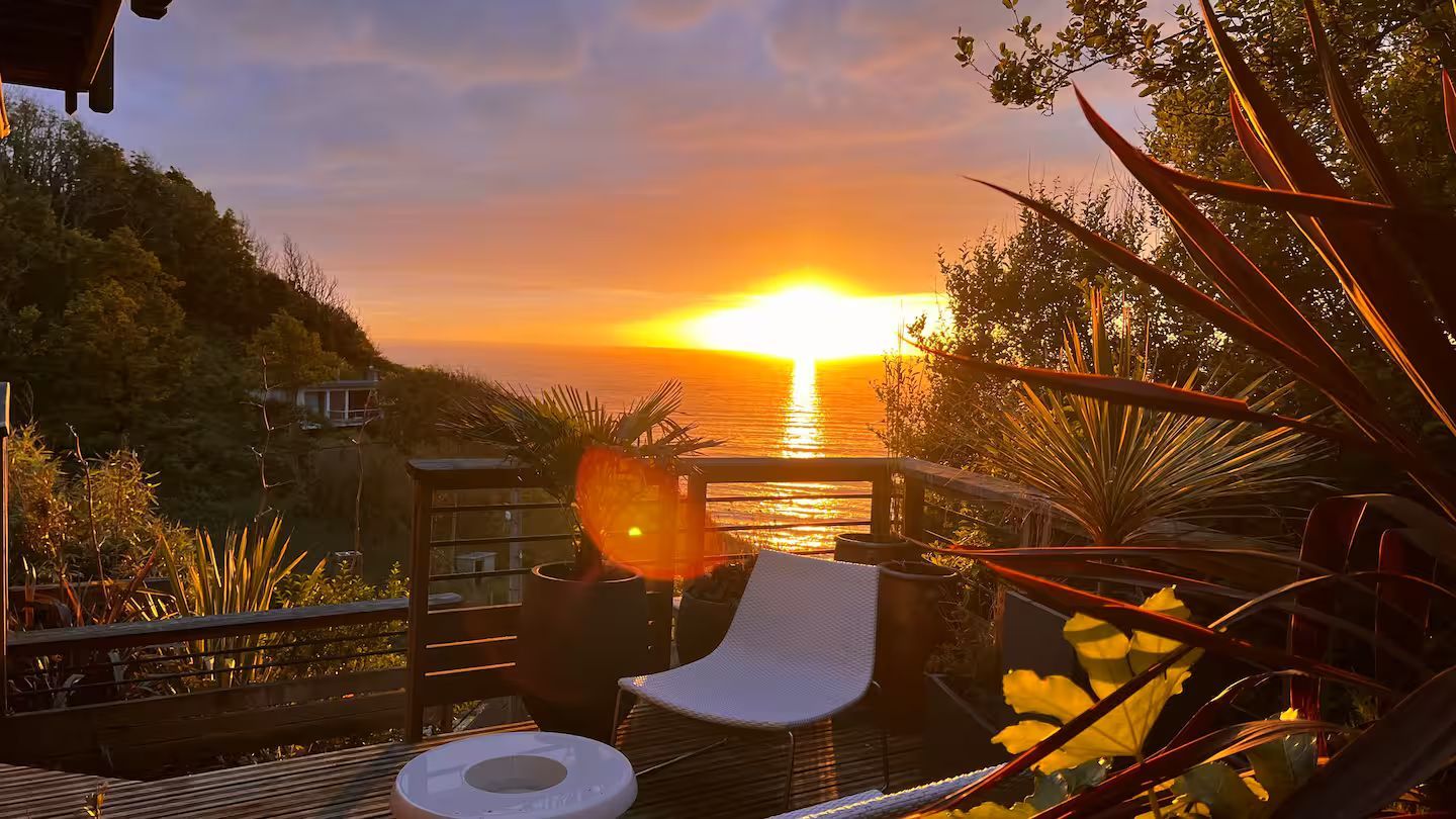 Un coucher de soleil sur l'océan avec une chaise au premier plan