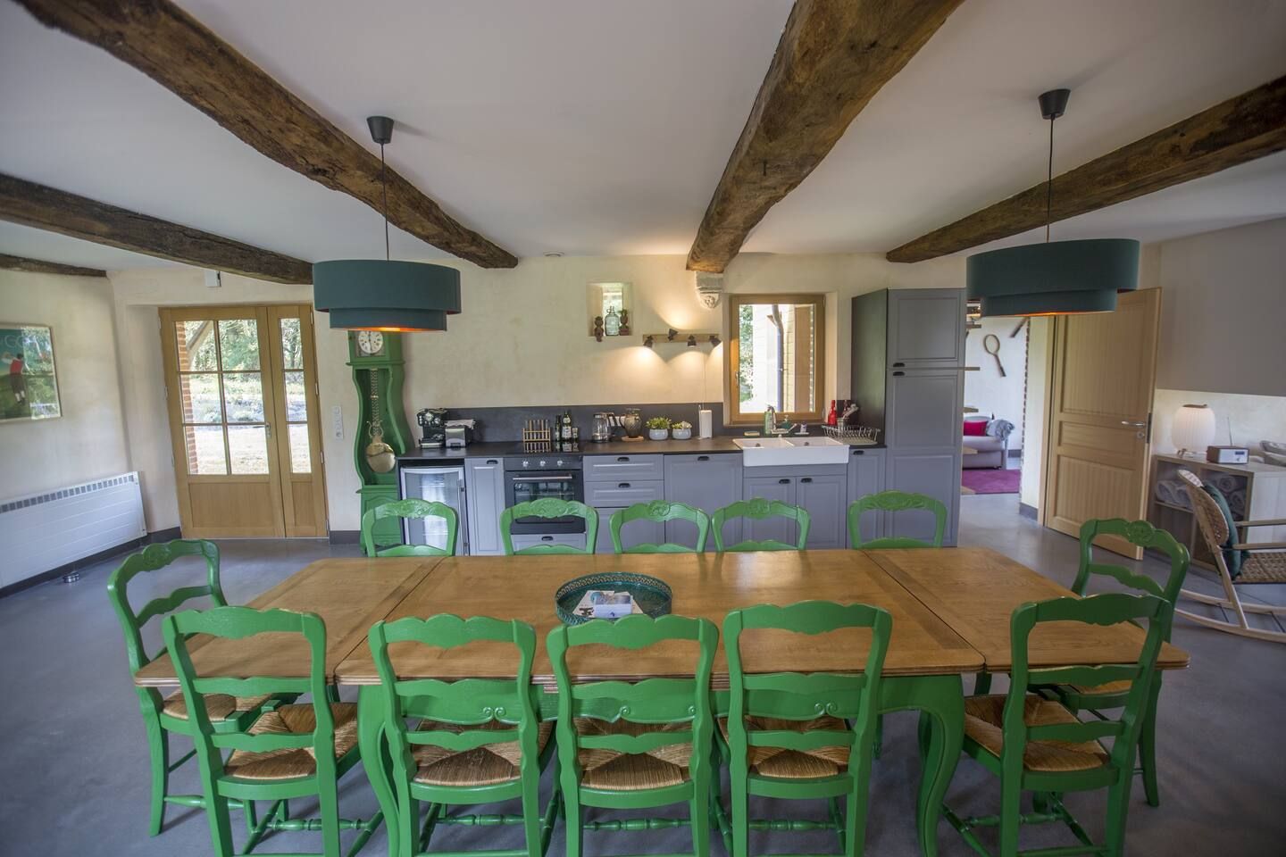 Grande salle à manger avec une table et la cuisine pour plusieurs convives dans le gite du domaine de la valaine à Etretat