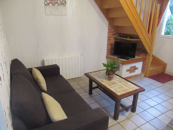 Salon avec canapé marron, table basse en bois et escalier.