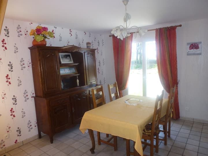 Salle à manger avec buffet en bois, table, chaises et rideaux rouges.