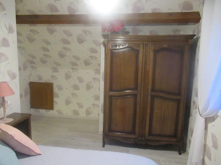 Chambre avec armoire en bois, table de chevet et papier peint à motifs.