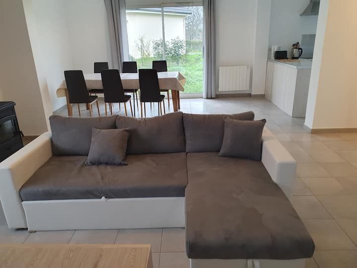 Salon moderne avec canapé d'angle gris et table à manger près des portes coulissantes en verre