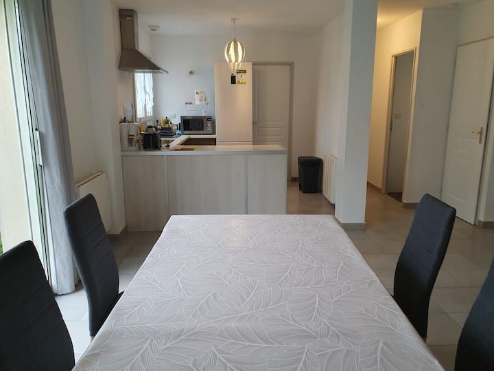 Table à manger dans une cuisine ouverte et lumineuse avec des armoires blanches et des chaises noires