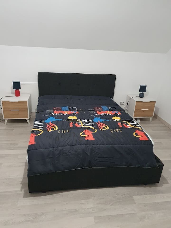 Chambre avec un couvre-lit noir, une couverture à motifs colorés et des tables de chevet assorties avec lampes.