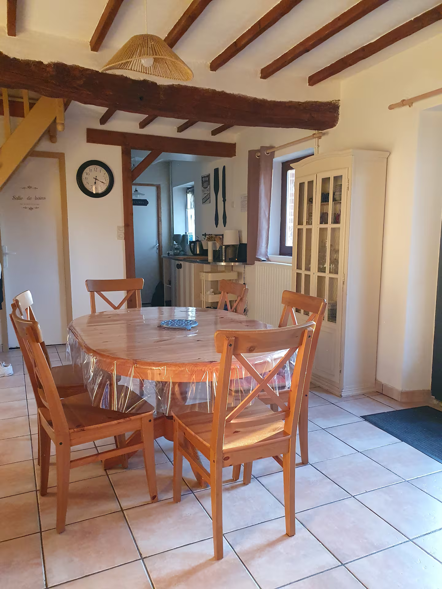 Une salle à manger avec une table et des chaises et une horloge au mur.
