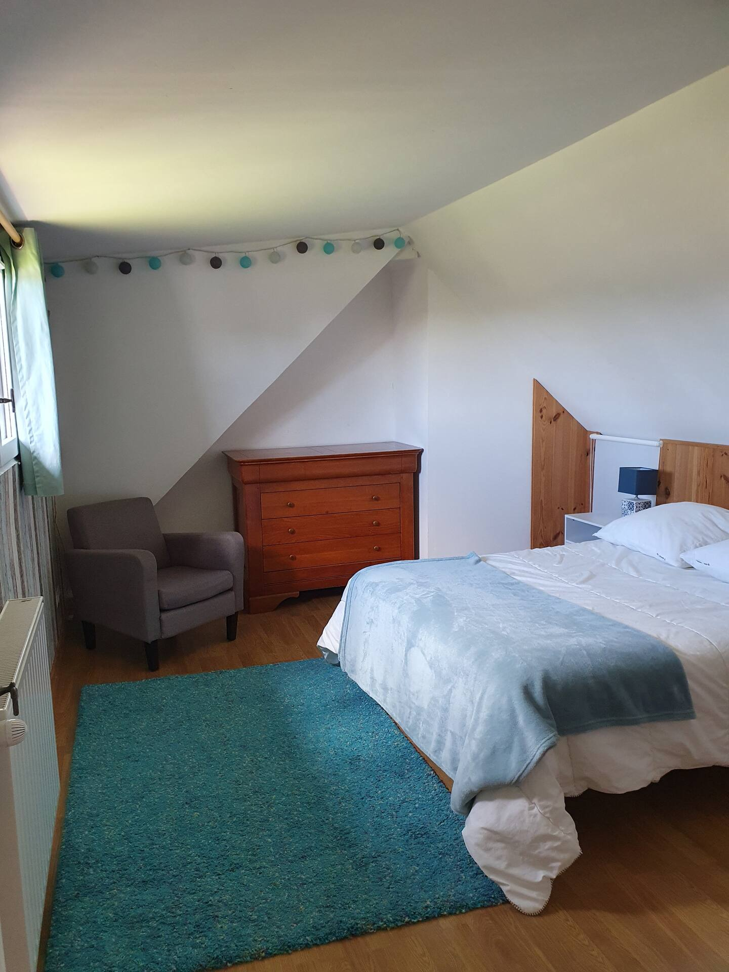 Une chambre avec un lit, une chaise, une commode et un tapis.
