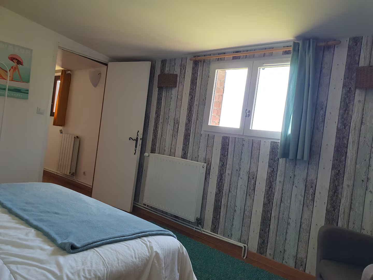 Une chambre avec un lit, une chaise, une fenêtre et du papier peint à rayures.