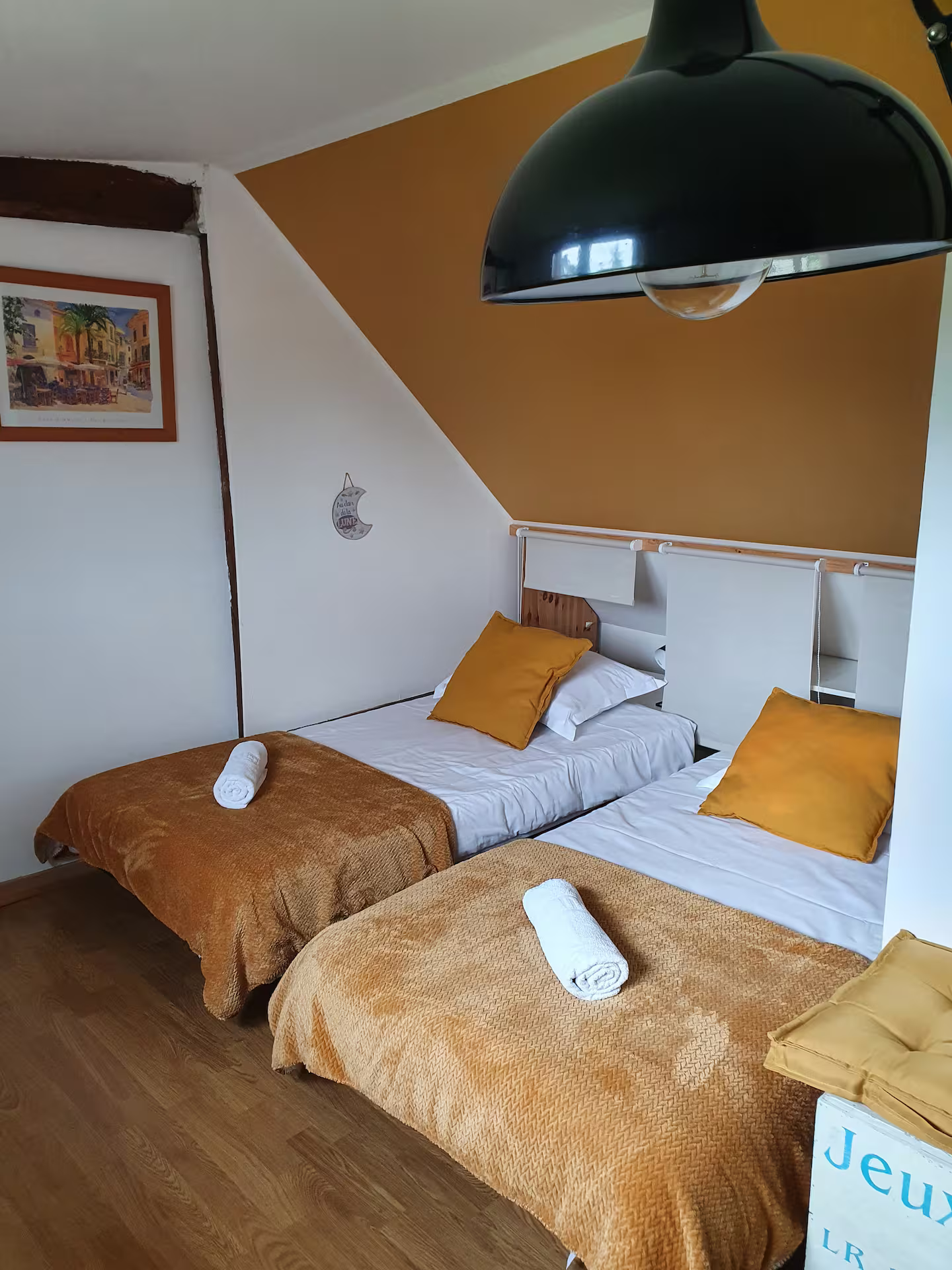 Une chambre avec deux lits, une lampe et un tableau au mur.