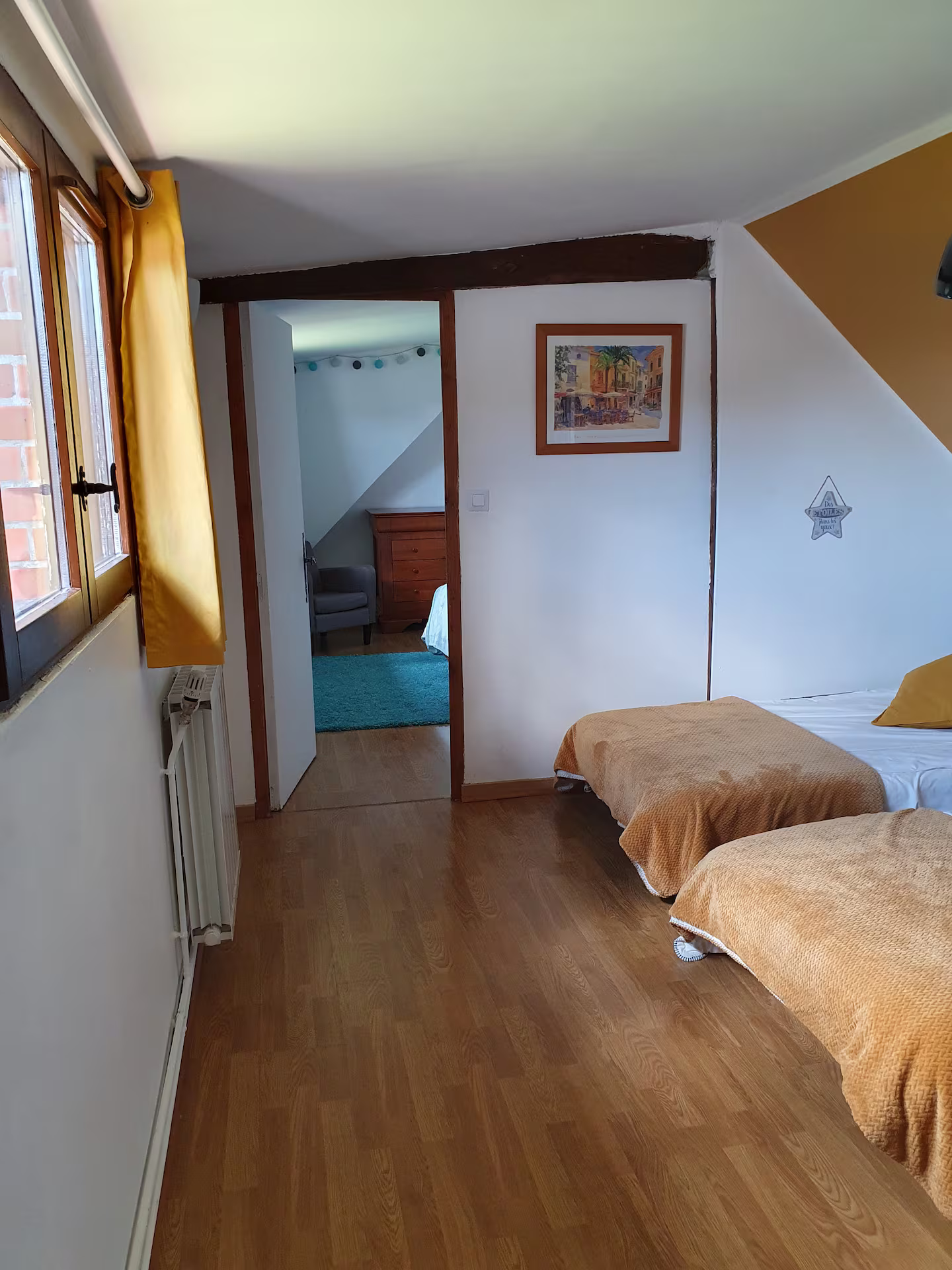 Une chambre avec deux lits et un tableau au mur.