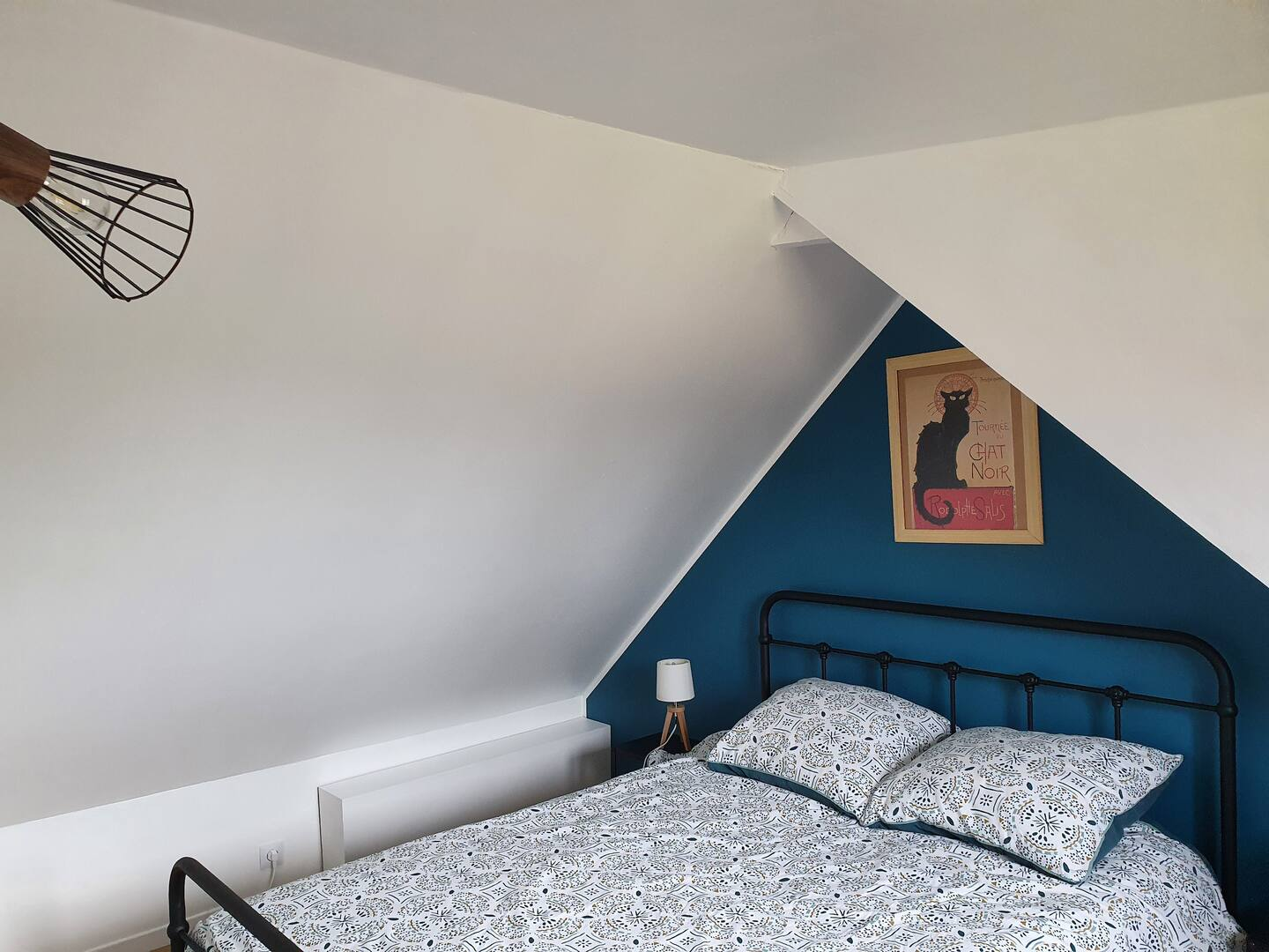 Il y a une photo d'un chat sur le mur au dessus du lit.