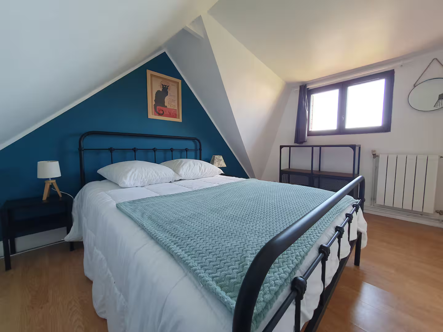Une chambre avec un lit, une table de chevet, une lampe et un radiateur.