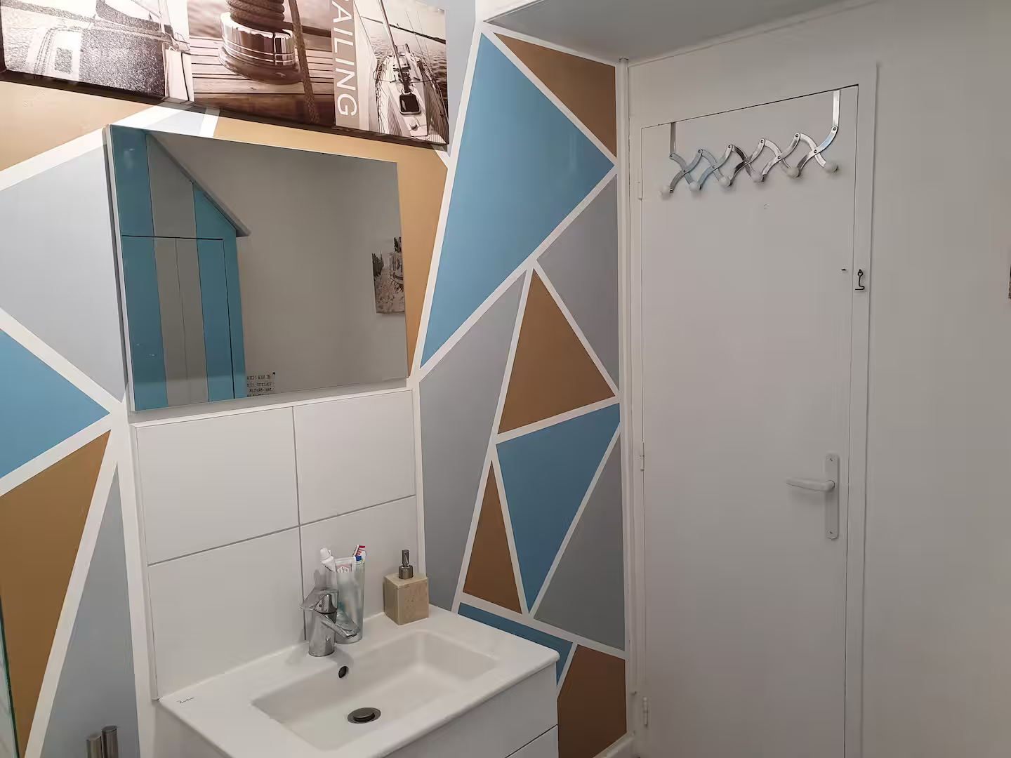 Une salle de bain avec un lavabo, un miroir et des murs peints géométriques