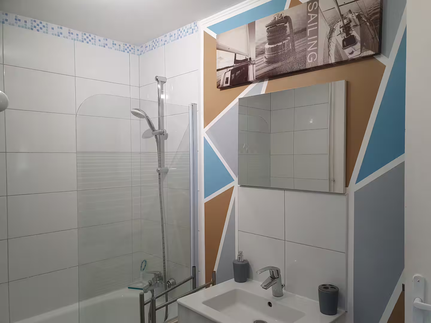 Une salle de bain avec lavabo, miroir, baignoire et douche.