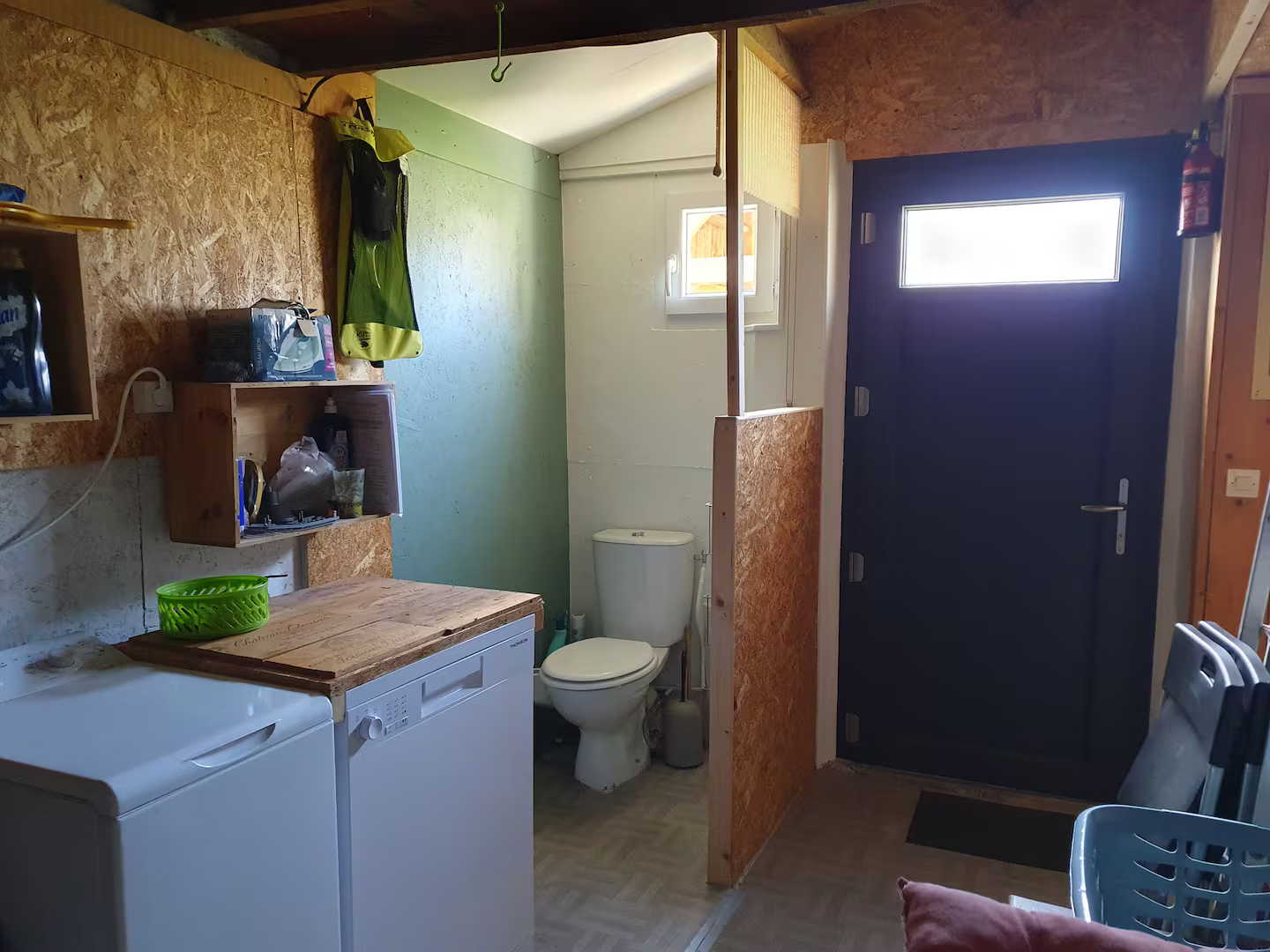 Une salle de bain avec toilettes, laveuse et sécheuse et une porte.