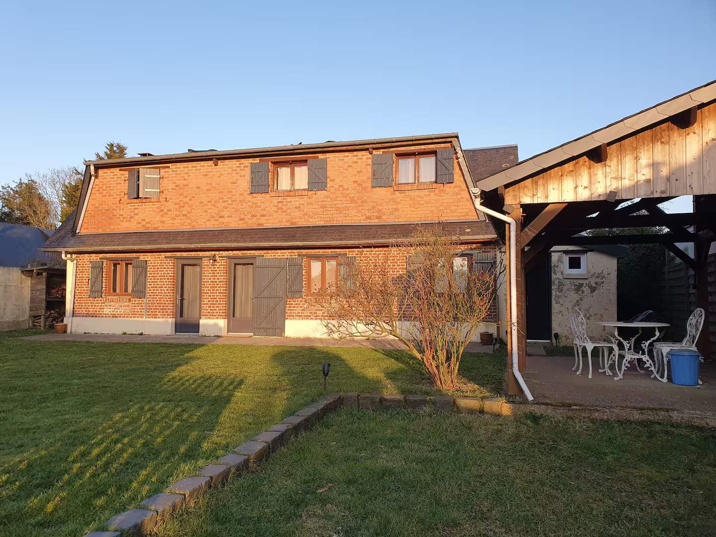 Une grande maison en briques avec un patio couvert devant