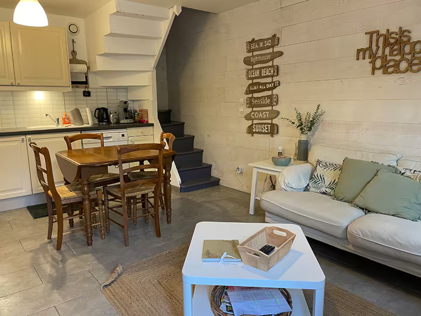 Un salon avec un canapé, une table, des chaises et un escalier.