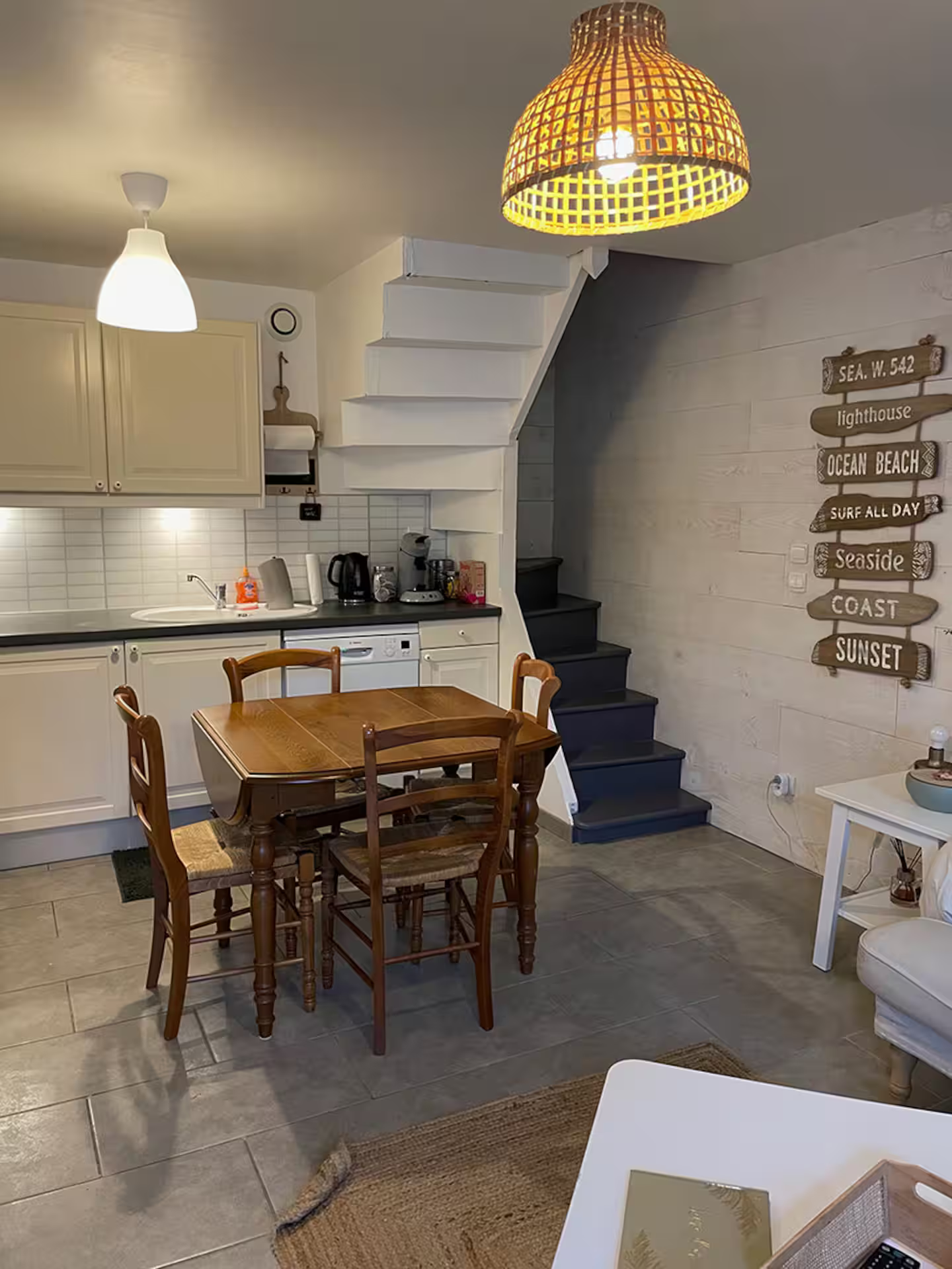 Une cuisine avec une table et des chaises et un escalier menant au deuxième étage.
