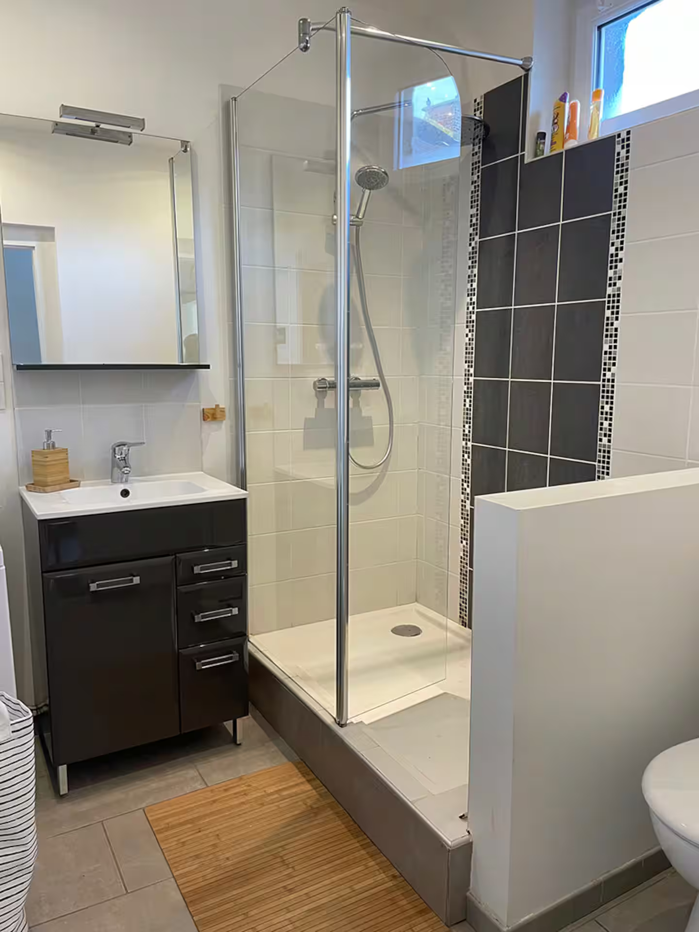 Une salle de bain avec douche, lavabo, WC et miroir.