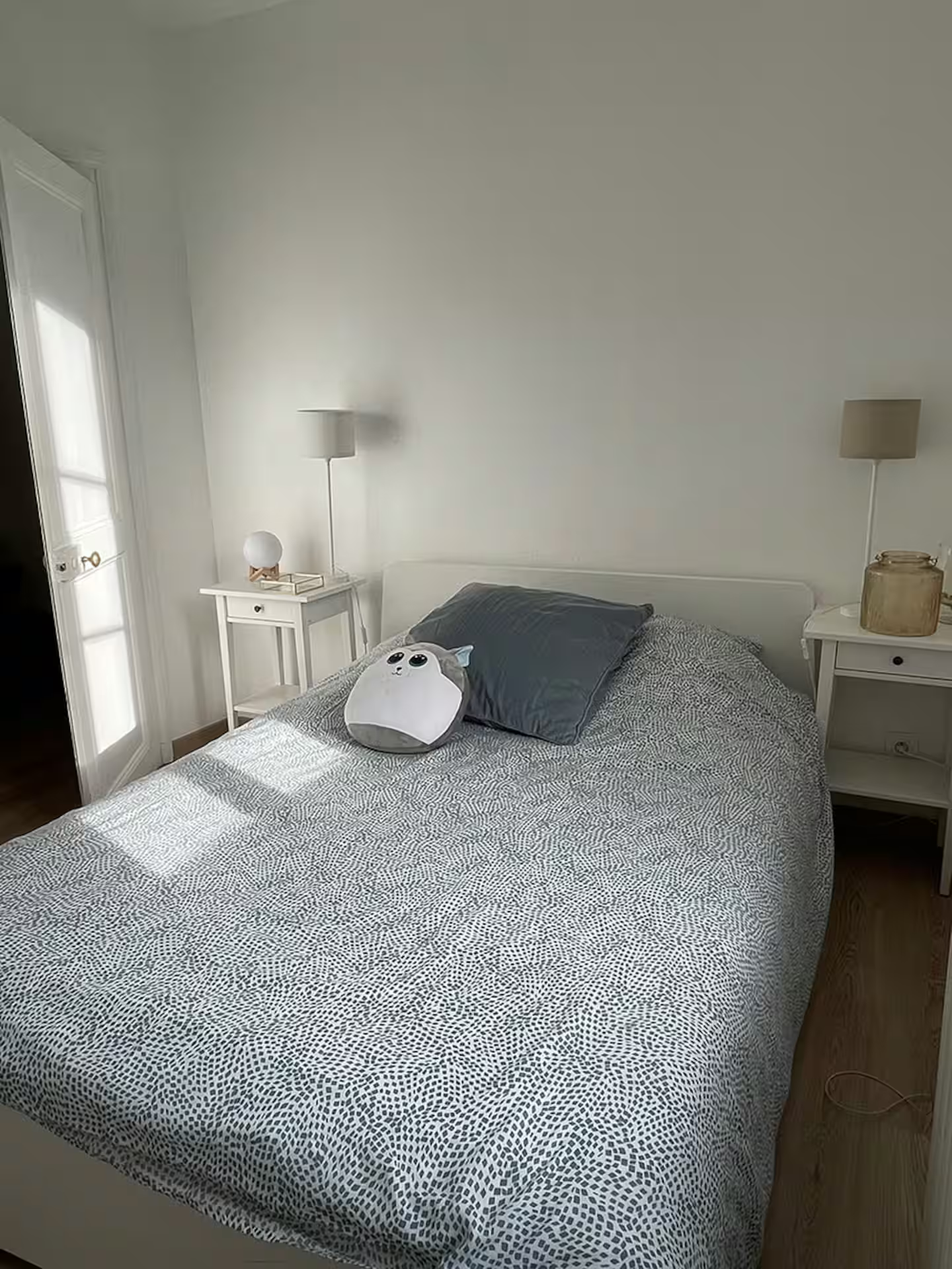 Une chambre avec un lit, une table de chevet, une lampe et une fenêtre.
