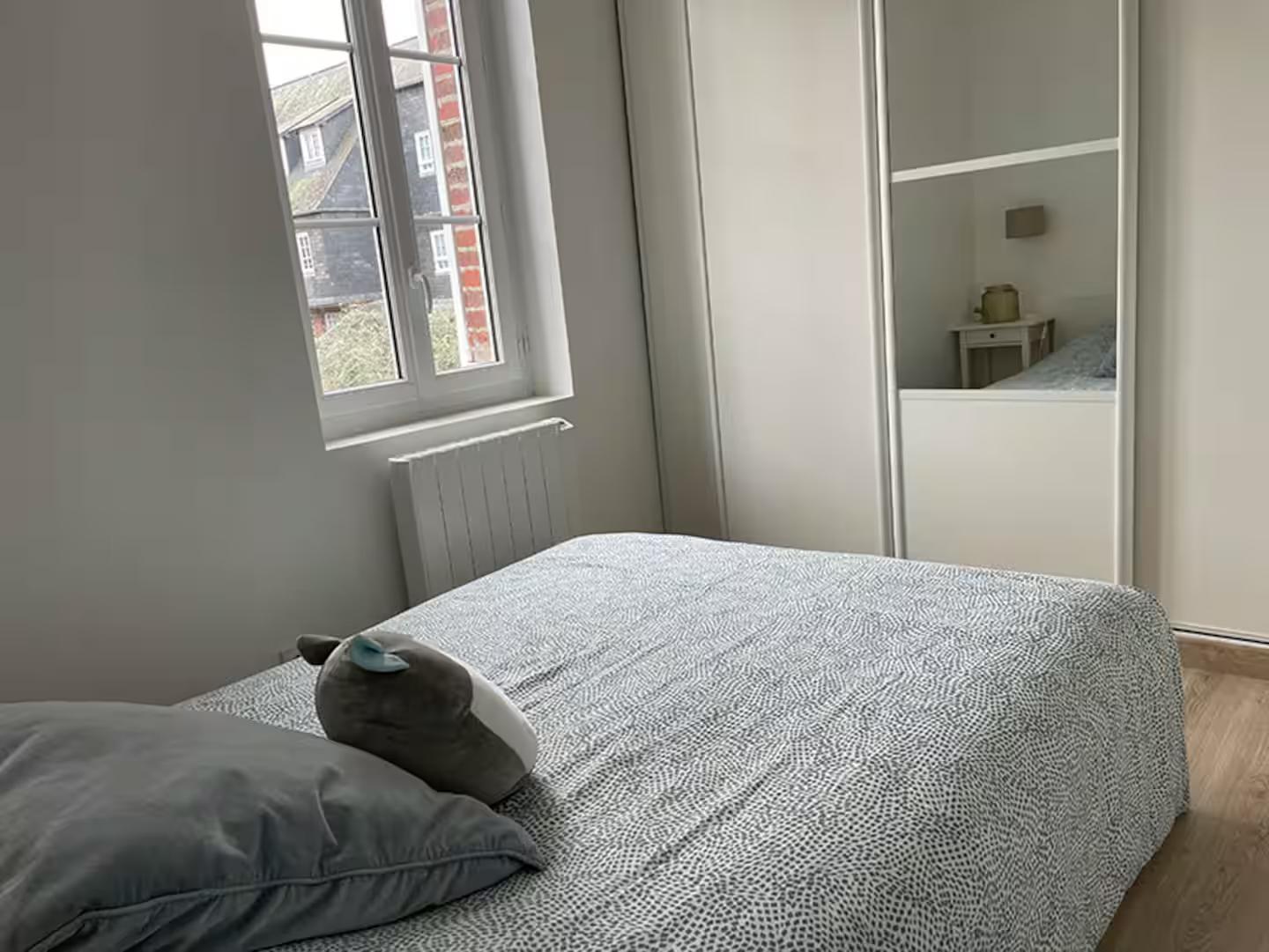 Une chambre avec un lit, une fenêtre, un placard et un miroir.