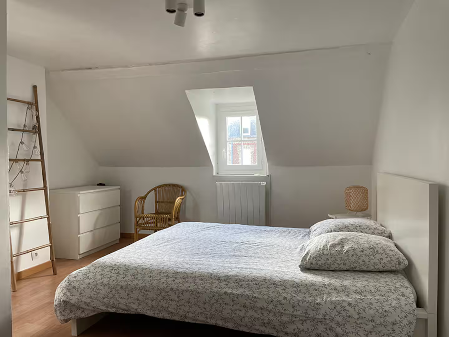 Une chambre avec un lit, une commode, une chaise et une fenêtre.