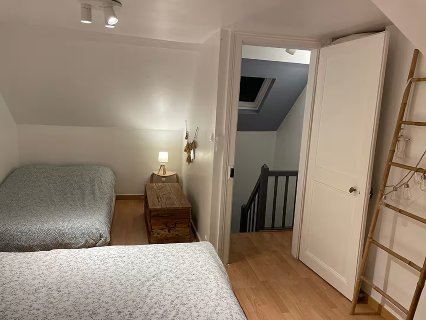 Une chambre avec deux lits et une échelle dans le coin.
