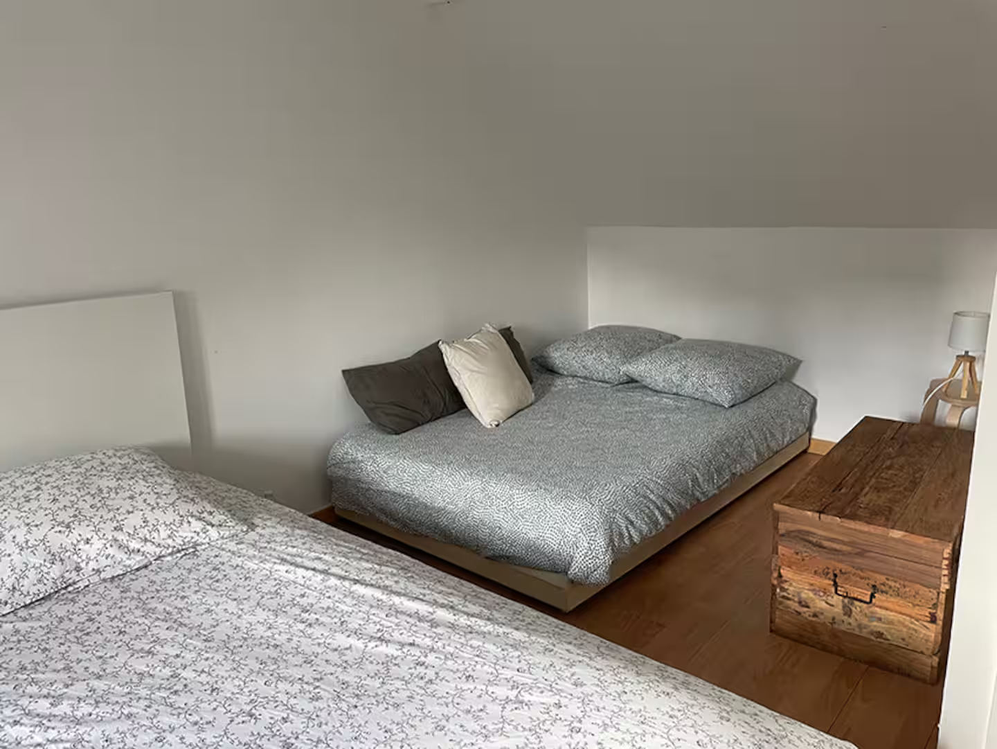 Une chambre avec deux lits et un coffre à l'étage.