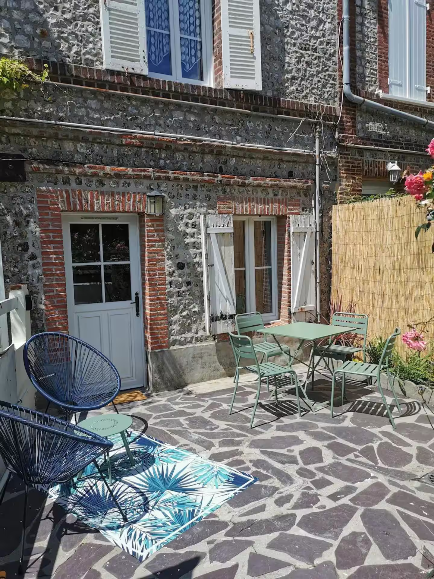 Un patio en pierre avec une table et des chaises devant un bâtiment en briques.