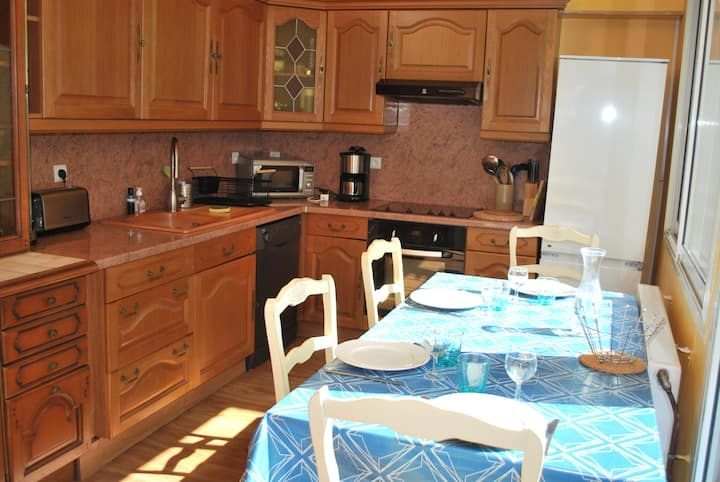 Cuisine avec placards en bois et table à manger recouverte d'une nappe bleue