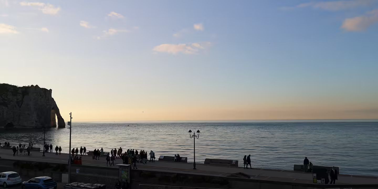 Un groupe de personnes debout sur une jetée surplombant l'océan au coucher du soleil.
