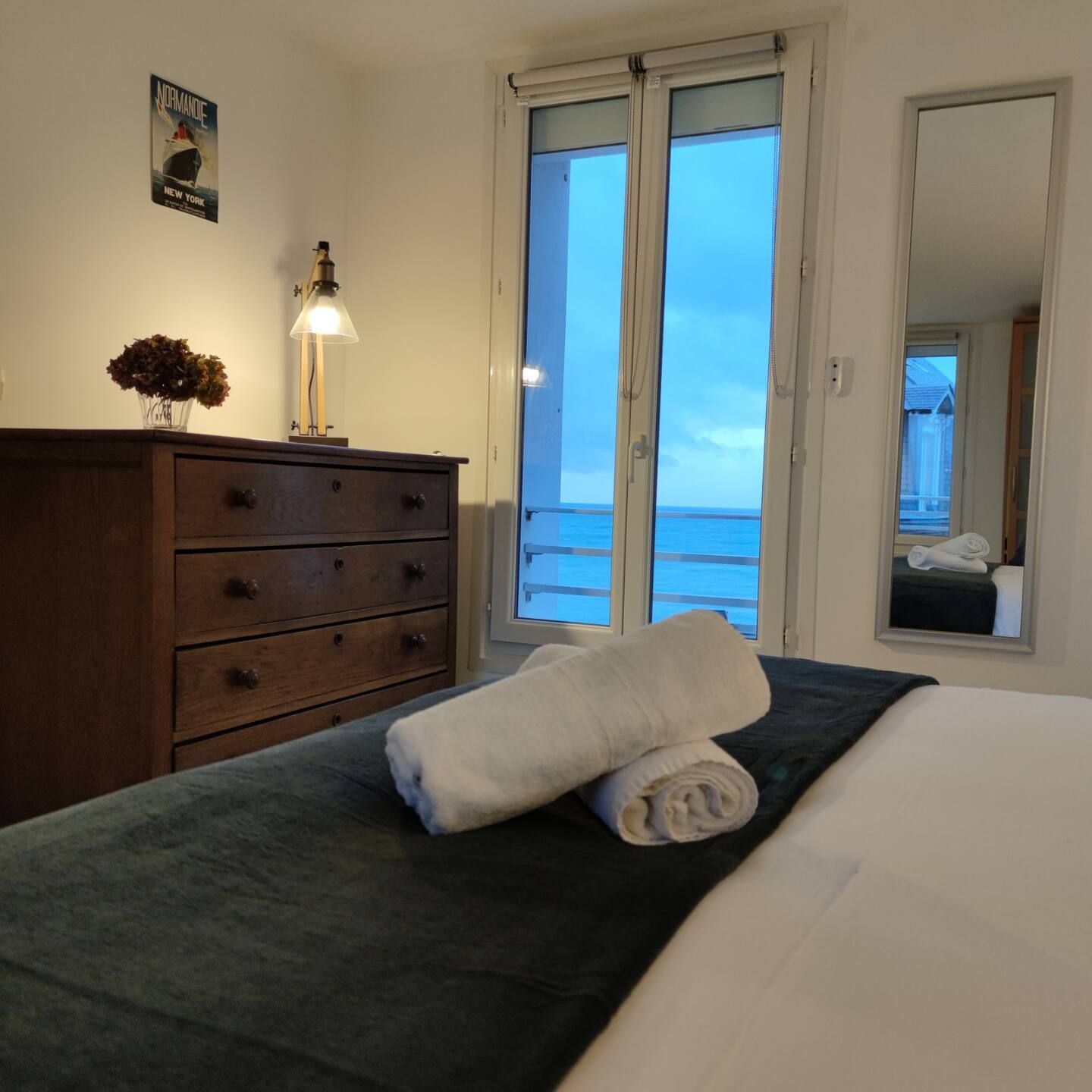 Une chambre avec deux serviettes sur le lit et une commode